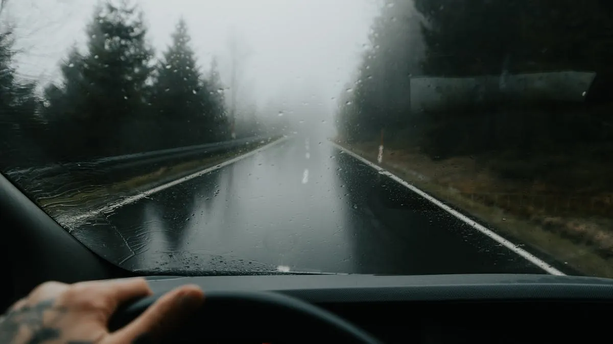 A car driving cautiously through thick fog with lights on