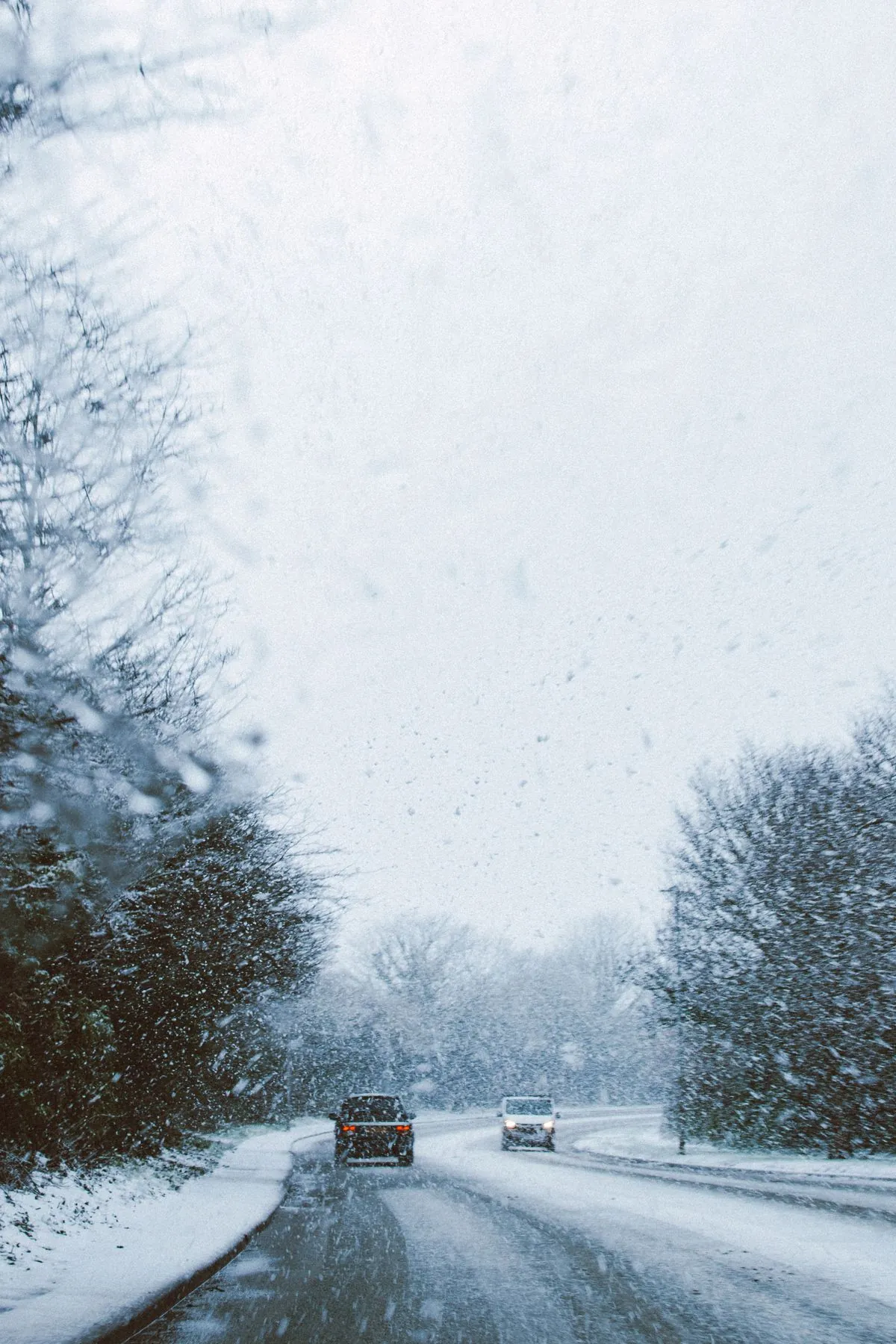 Cars driving on a snow-covered UK road fitted with winter tyres